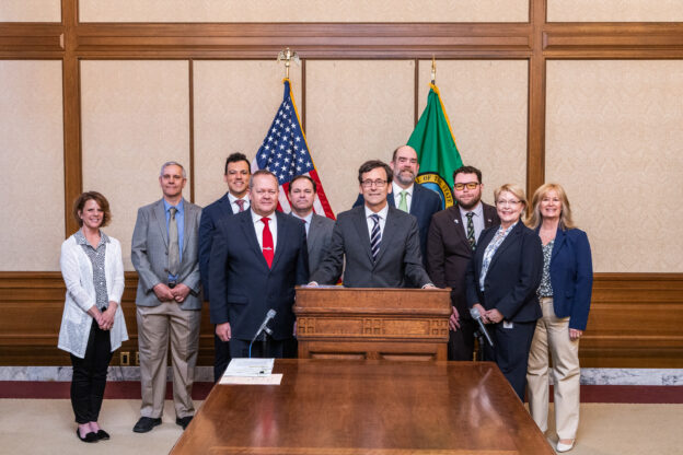 Front row, L to R: Sen. Matt Boehnke, R-Kennewick, Gov. Bob Ferguson, and Virginia Hall, SLA, Office of Sen. Boehnke. Back row, L to R: Dawn Boehnke, Derrek Wilson, Dept. of Ecology, Anthony “Tony” Abbot, Dept. of Ecology, Cameron Long, SRC Policy, WA State Senate, Ken Camp, Dept. of Ecology, Micheal Leone, Session Intern, Office of Sen. Boehnke, and Christina McNair, Session Aide, Office of Sen. Boehnke/Credit: Washington State Senate